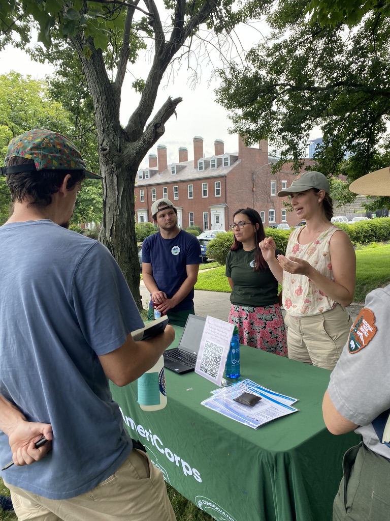 Staff with the National Park Service stand at a table talking to teachers.