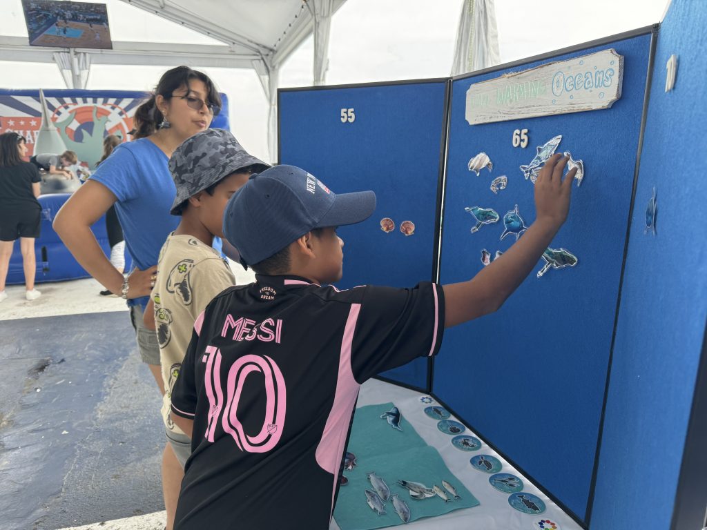 A young boy puts a marine animal cut-out onto a felt board, titled "Our Warming Oceans."