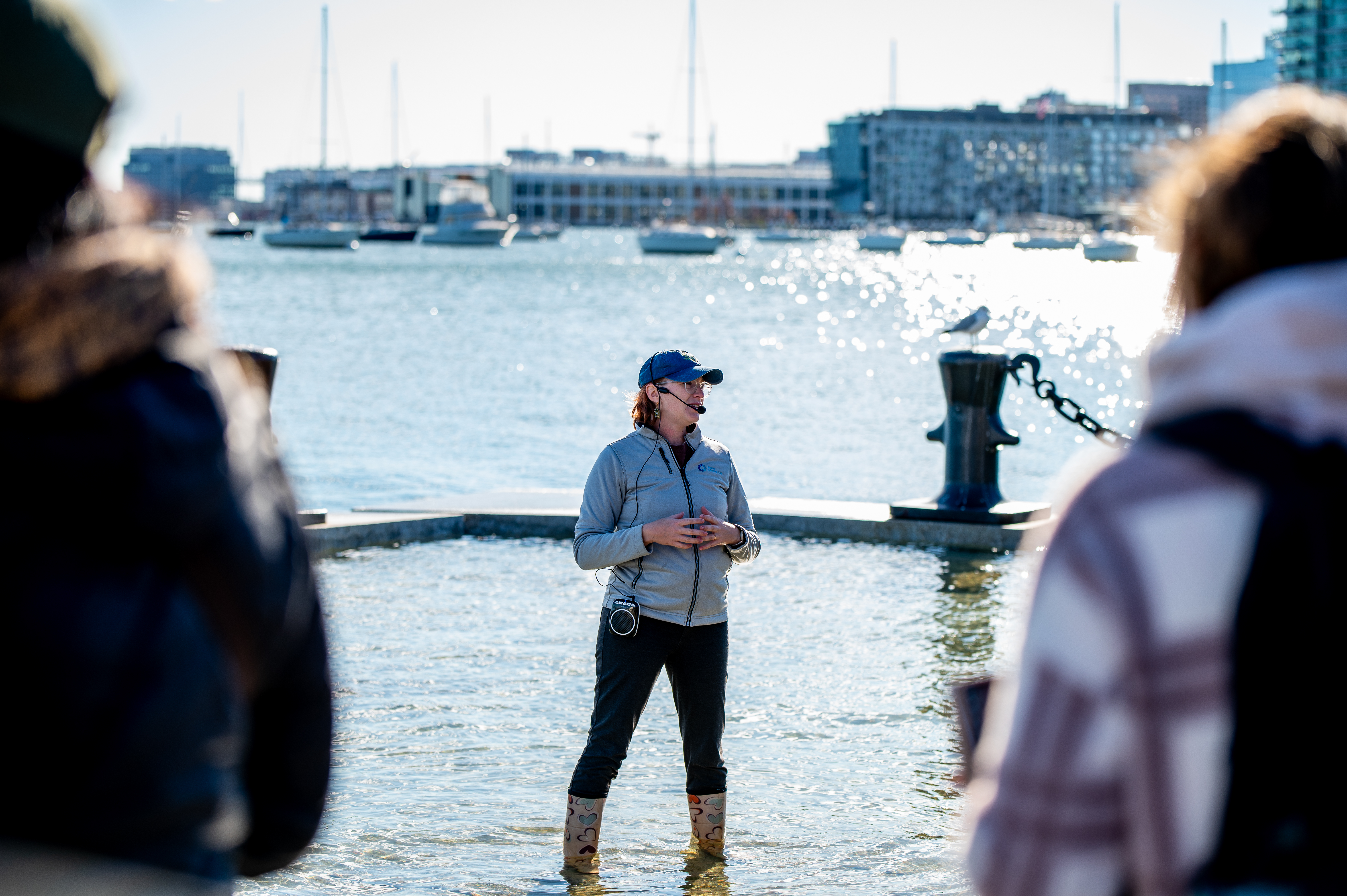 Woman standing on a flooding wharf, speaking to a crowd.