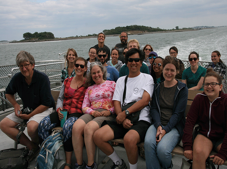 group of people smiling on a boat tour on the ocean