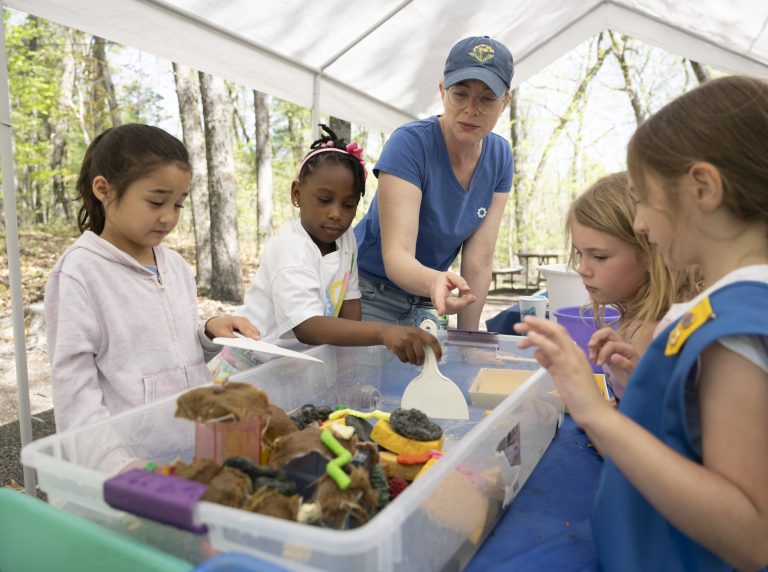 A group of students gathered around a large bin with different water and materials inside