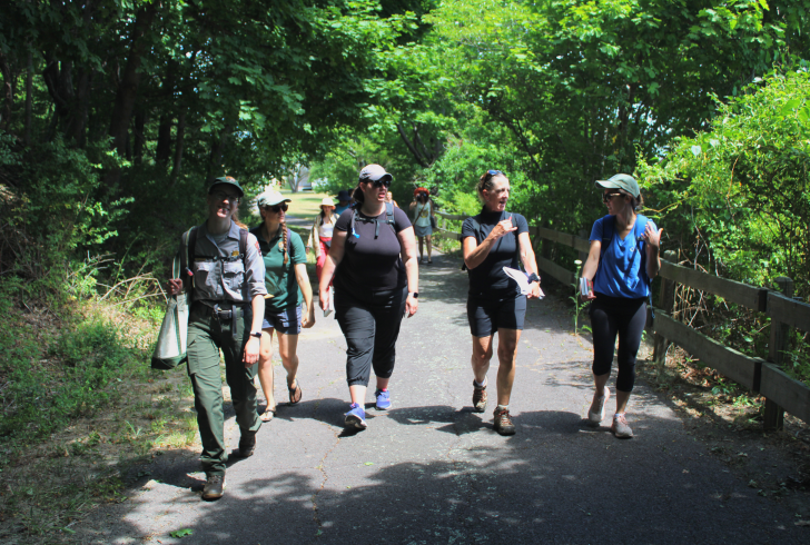 A group of people led by a Park Ranger walking down a path towards the camera.