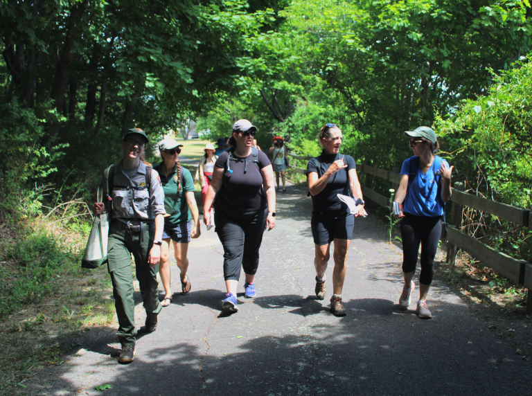 A group of people led by a Park Ranger walking down a path towards the camera.